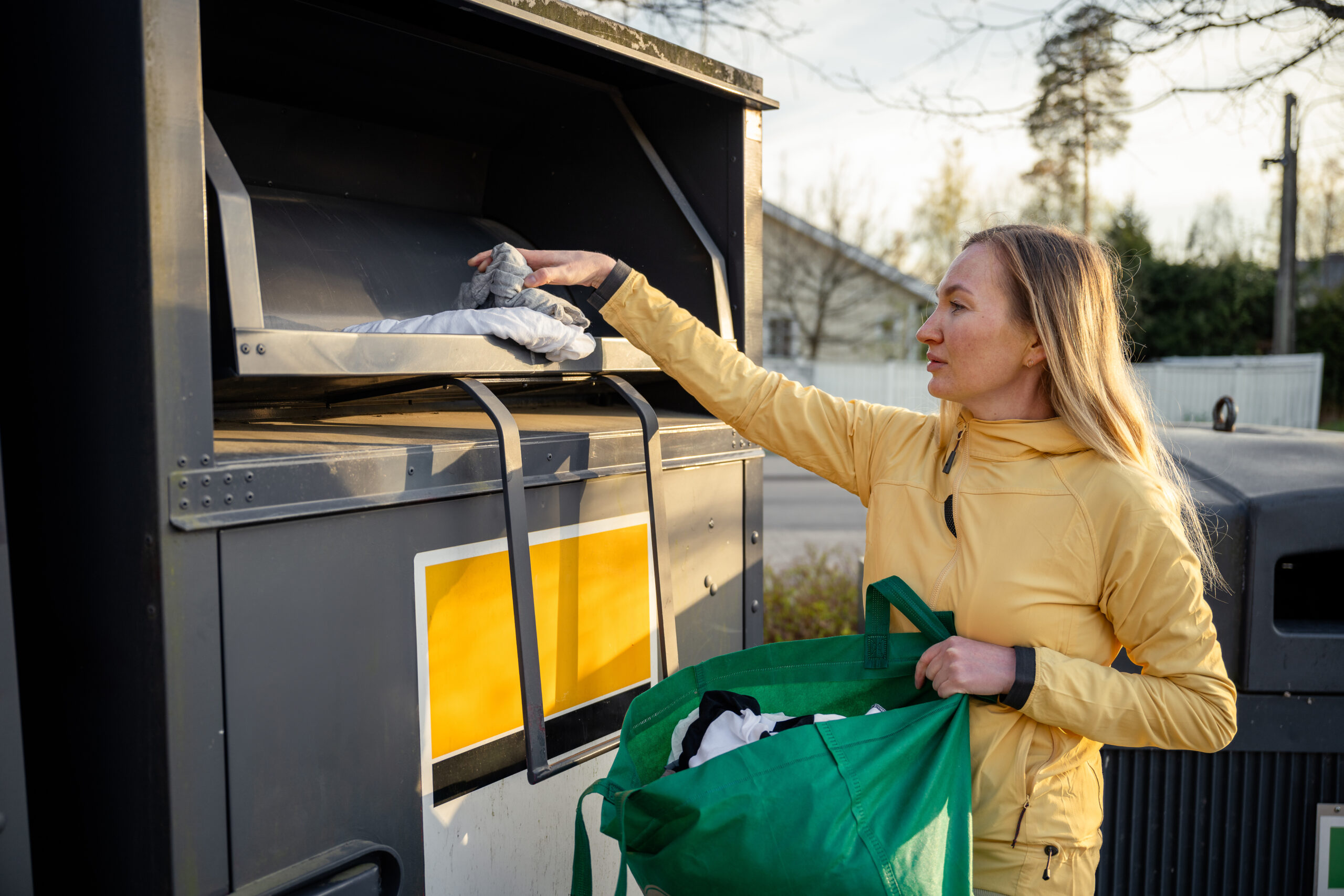 Woman placing old used clothes at recycling bins