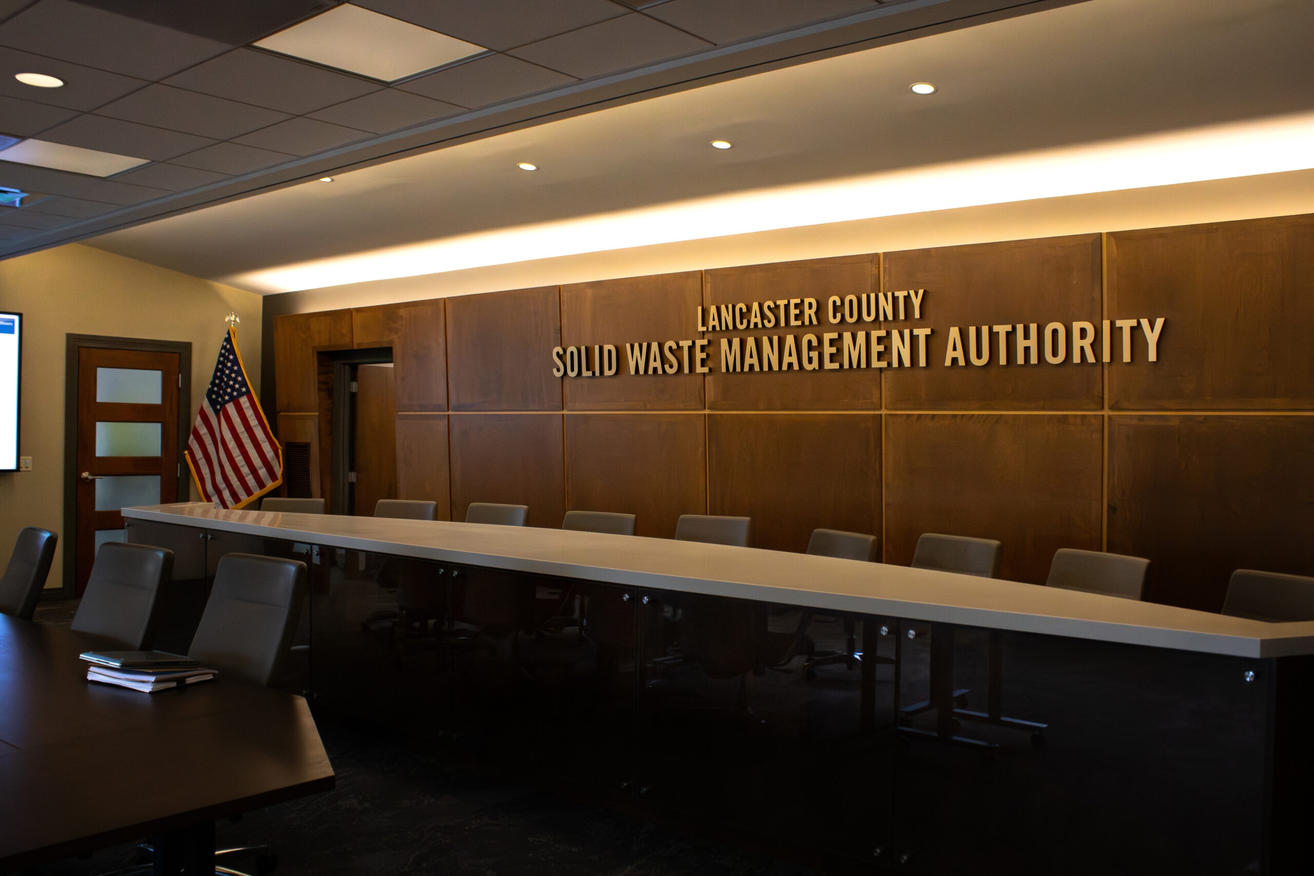 Board room featuring table and chairs lined up facing one way and words written on wall behind table